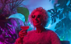 A lady with grey hair and sunglasses holding a cocktail