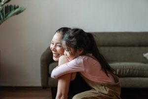 A young girl hugging her mother from behind